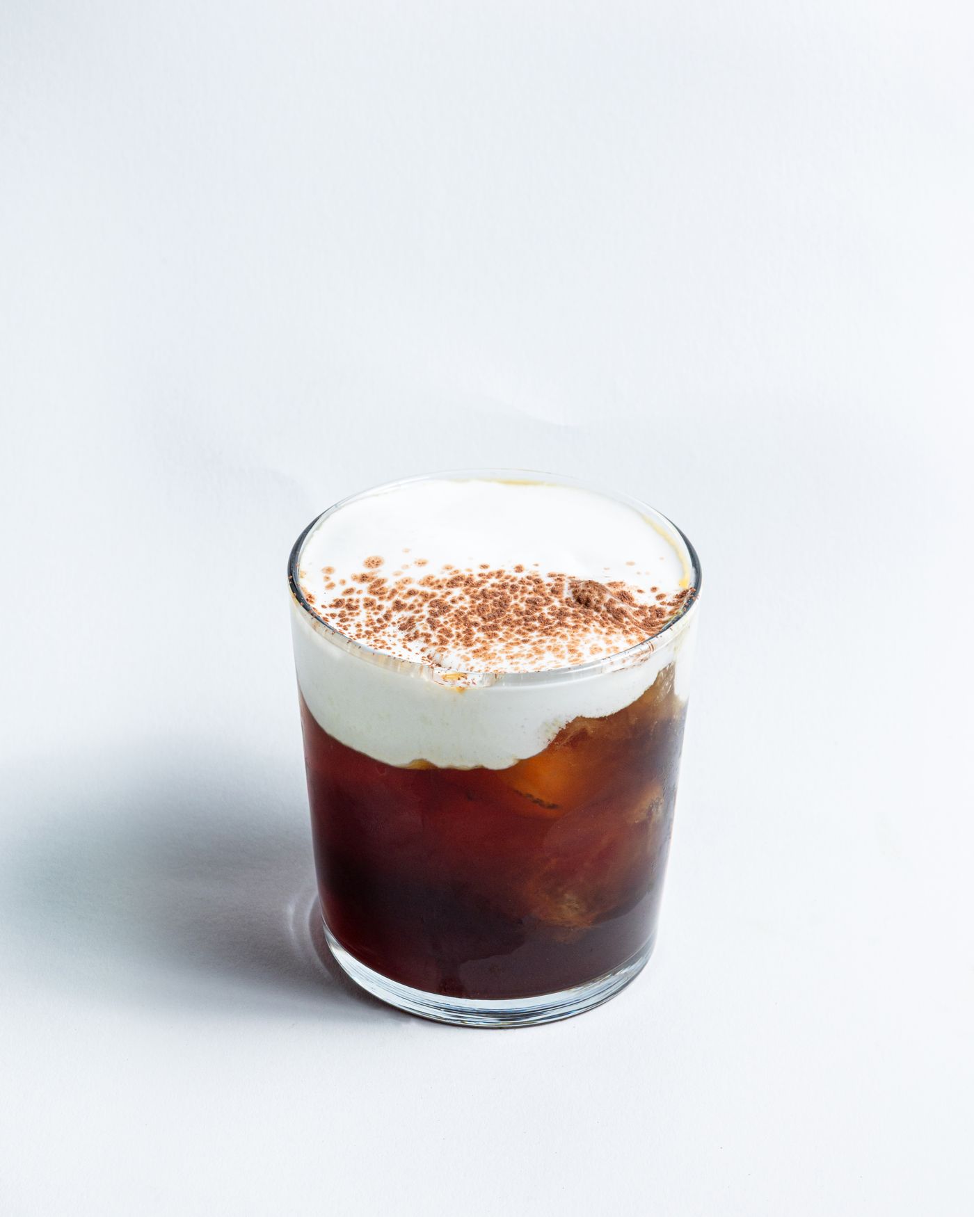 Iced coffee with cream and cocoa powder in a glass