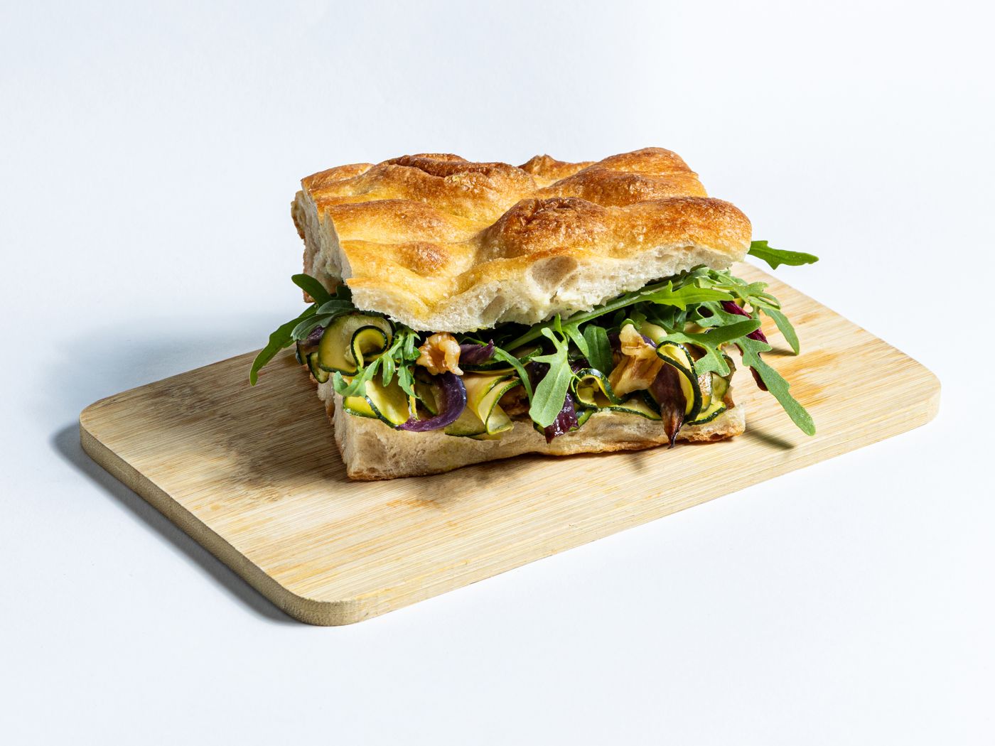 Belegte Focaccia mit Zucchini, Walnüssen, roten Zwiebeln und Rucola
